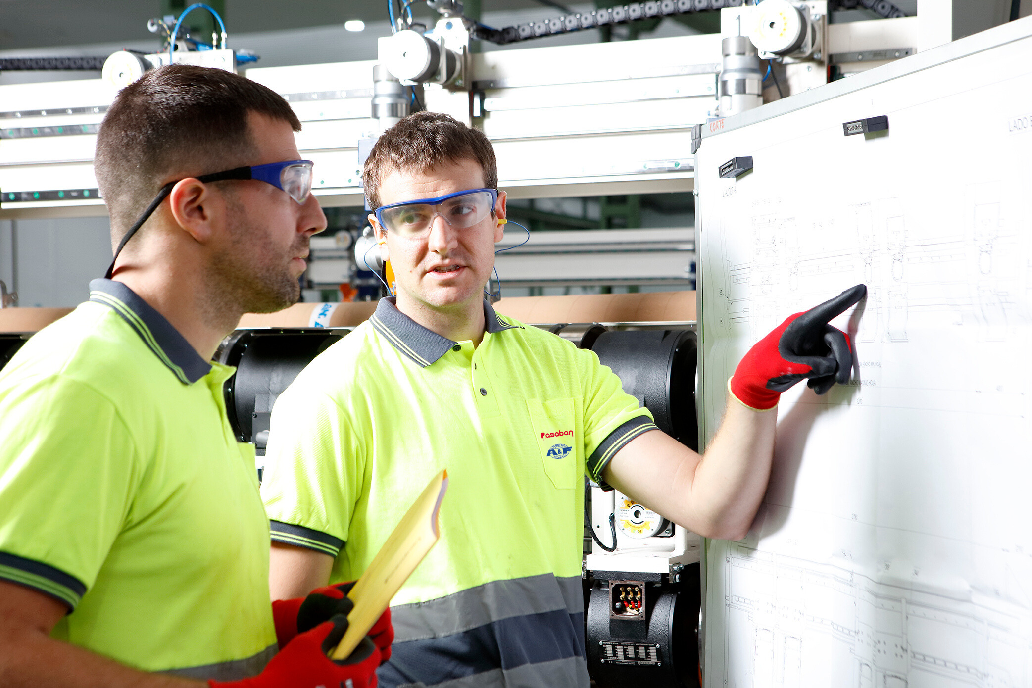 Pasaban technicians reviewing machine upgrade plans for paper converting equipment